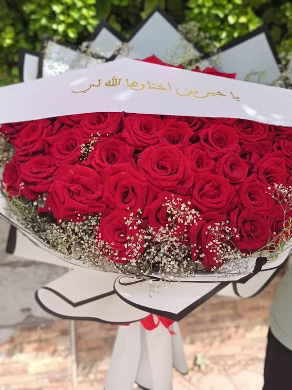 Bouquet de roses rouges avec ruban de calligraphie arabe dorée