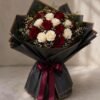 Un bouquet de luxe spectaculaire présentant un dôme de roses rouges souligné par une bordure perlée et un emballage architectural blanc plissé.